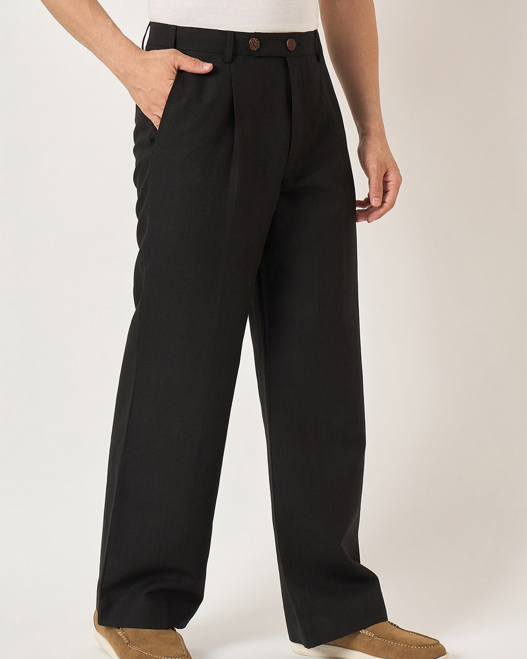 Person wearing black pleated pants on a white background