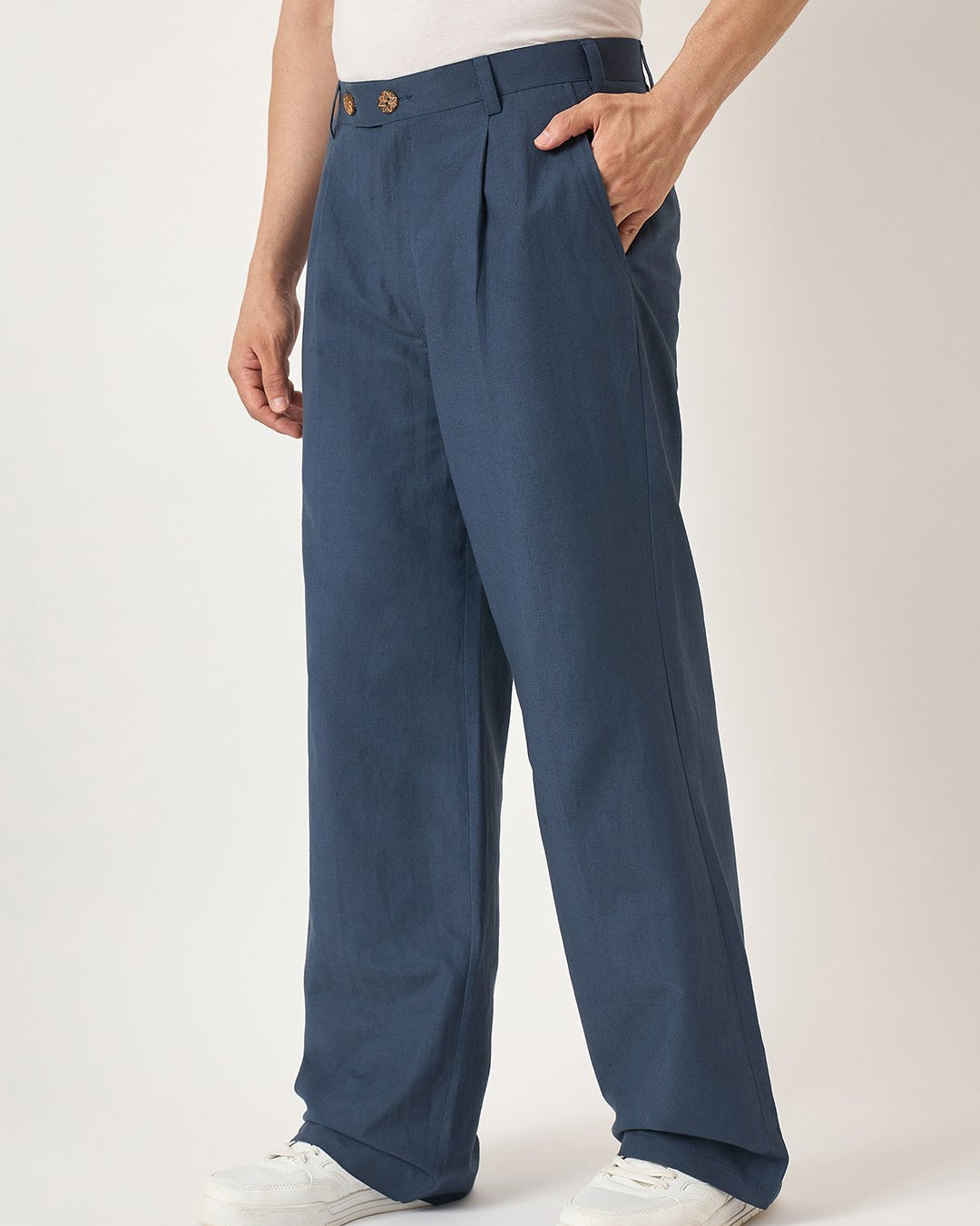 Person wearing blue pleated pants on a white background
