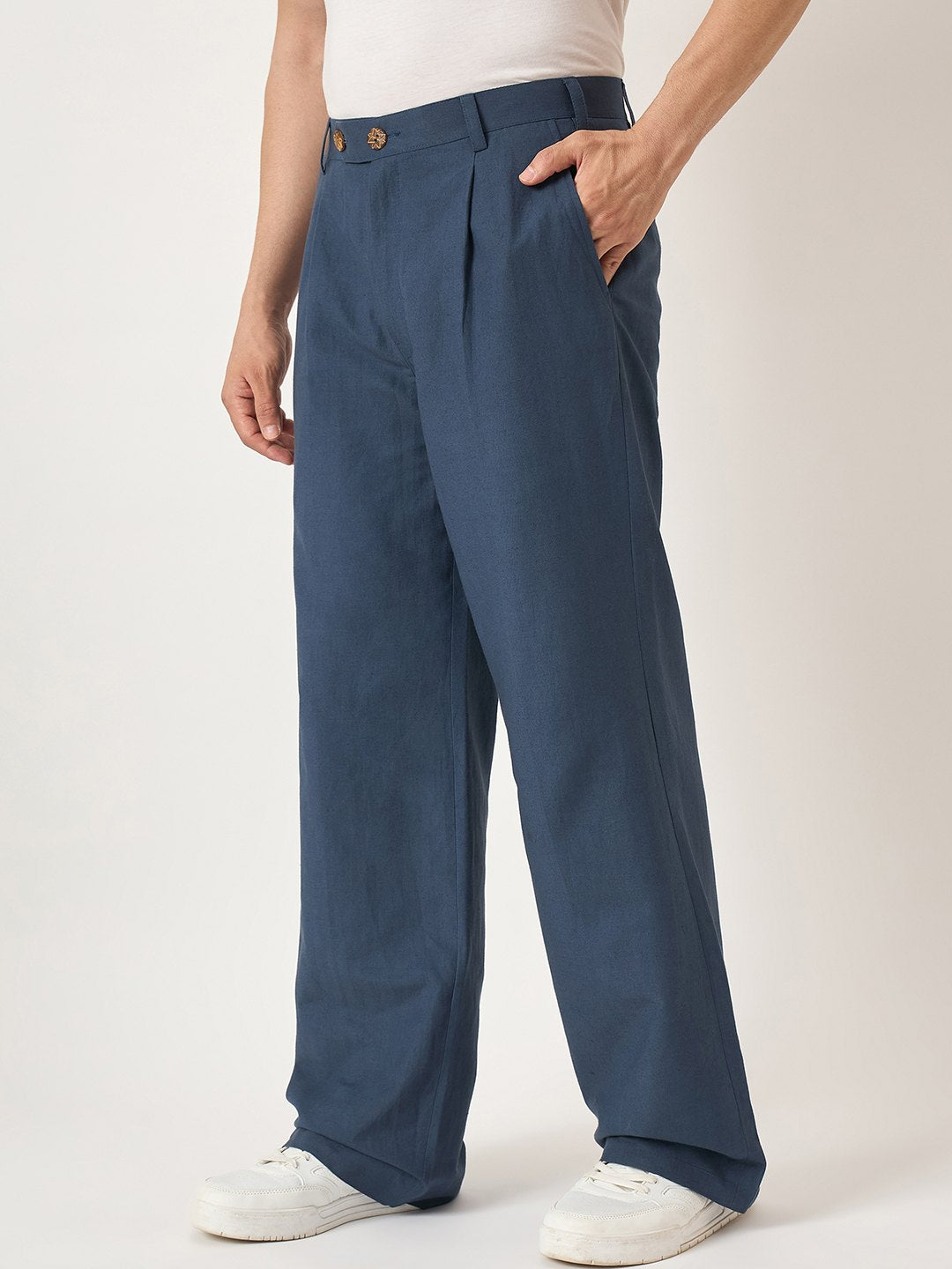 Person wearing blue pleated pants on a white background