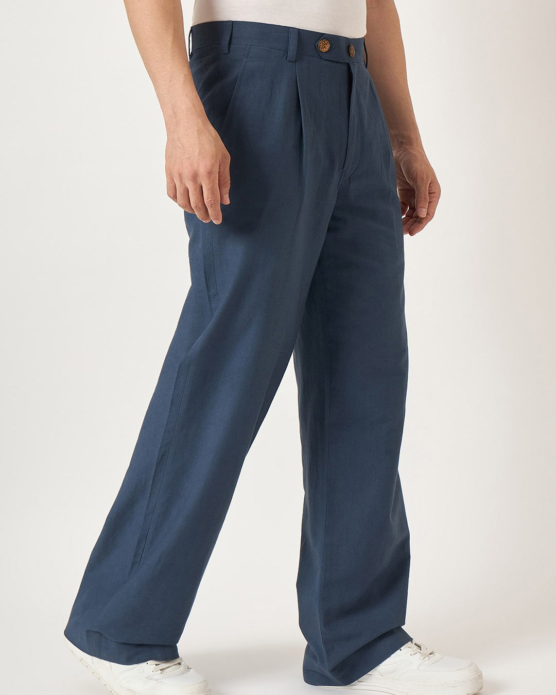 Person wearing blue pleated pants on a white background