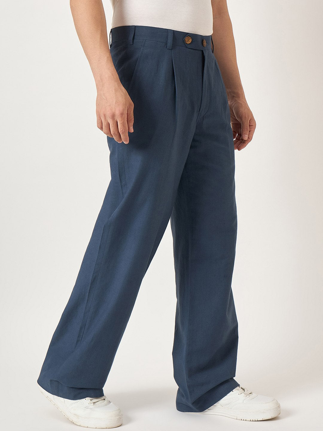 Person wearing blue pleated pants on a white background