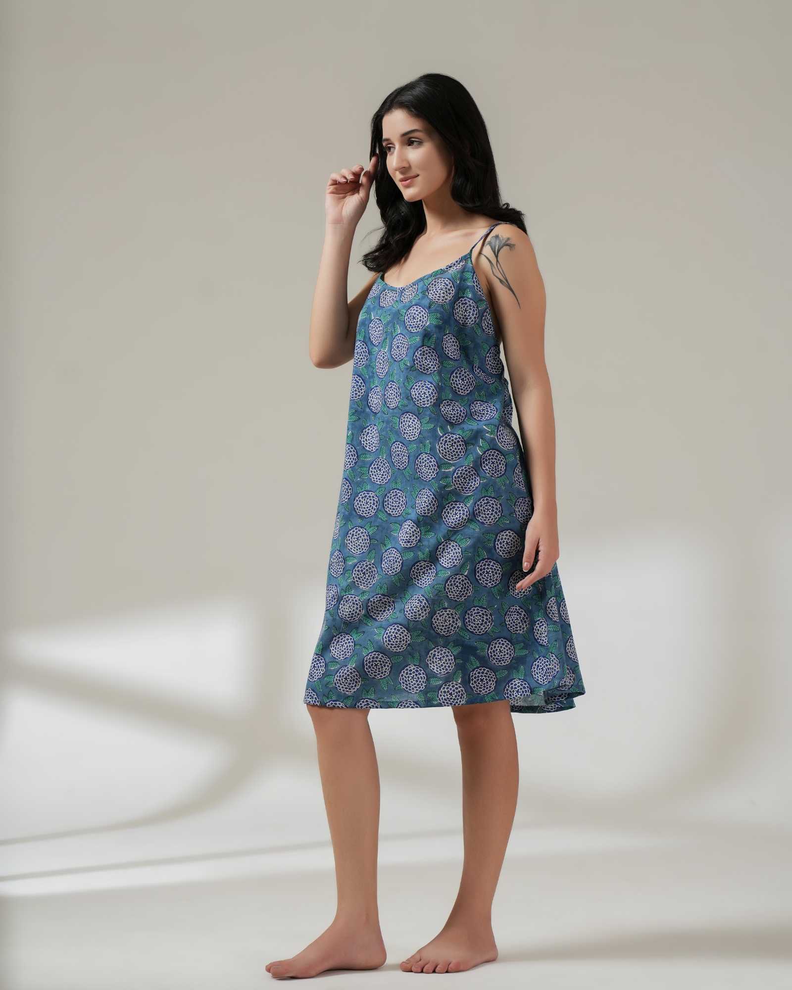 Woman wearing a blue patterned slip dress on a plain background