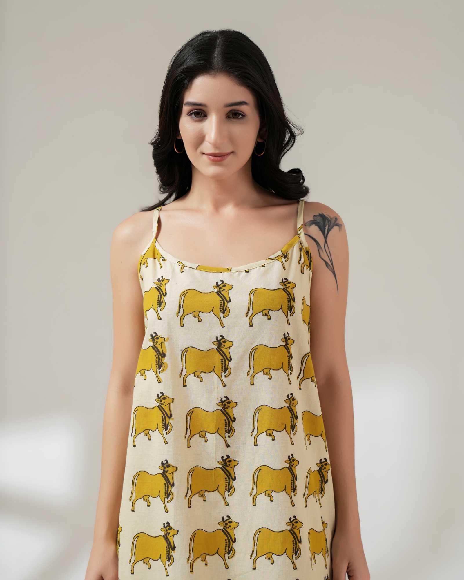 Woman wearing a sleeveless dress with yellow cow pattern on a plain background