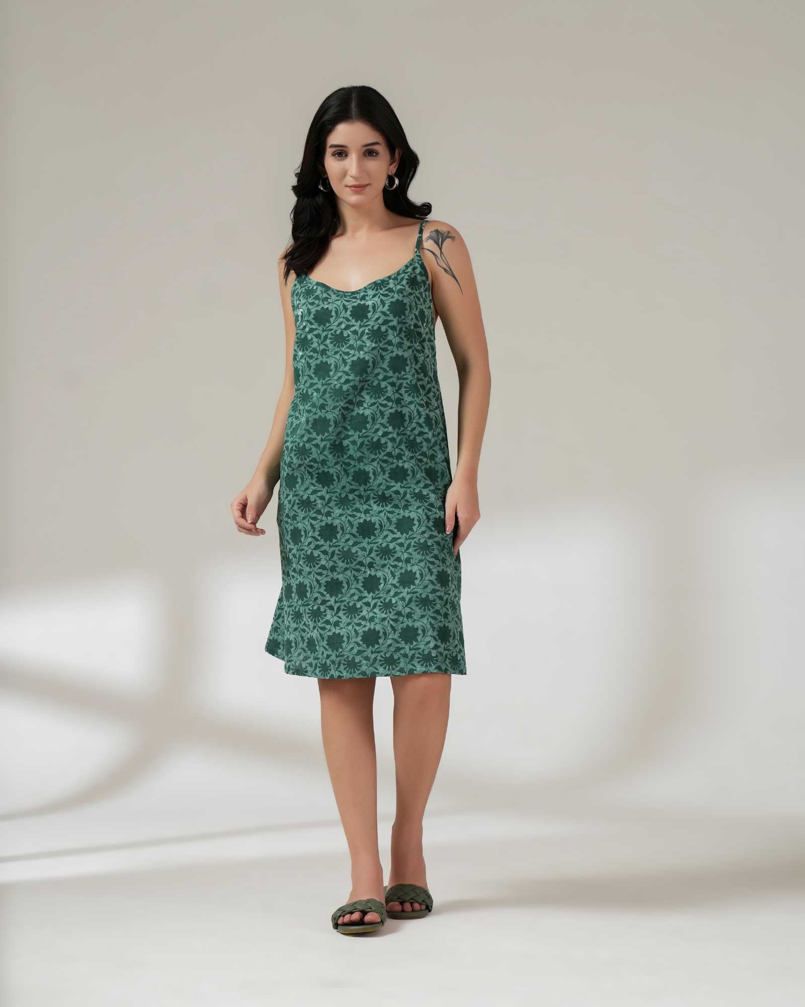 Woman wearing a green floral slip dress on a white background.