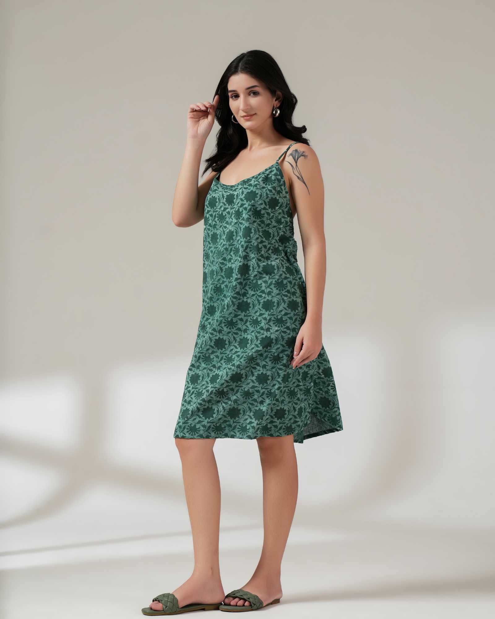 Woman wearing a green floral dress against a plain background