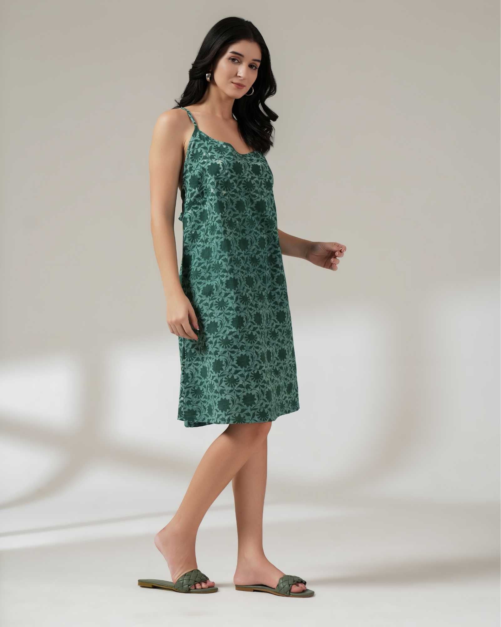 Woman wearing a green floral dress against a plain background