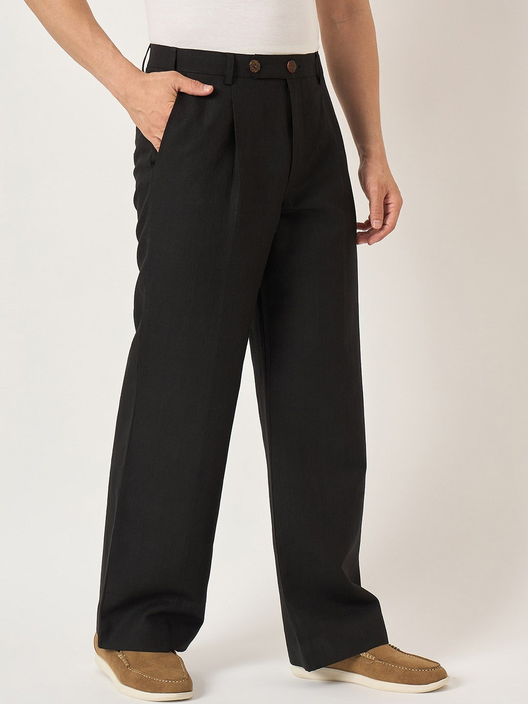 Person wearing black pleated pants on a white background