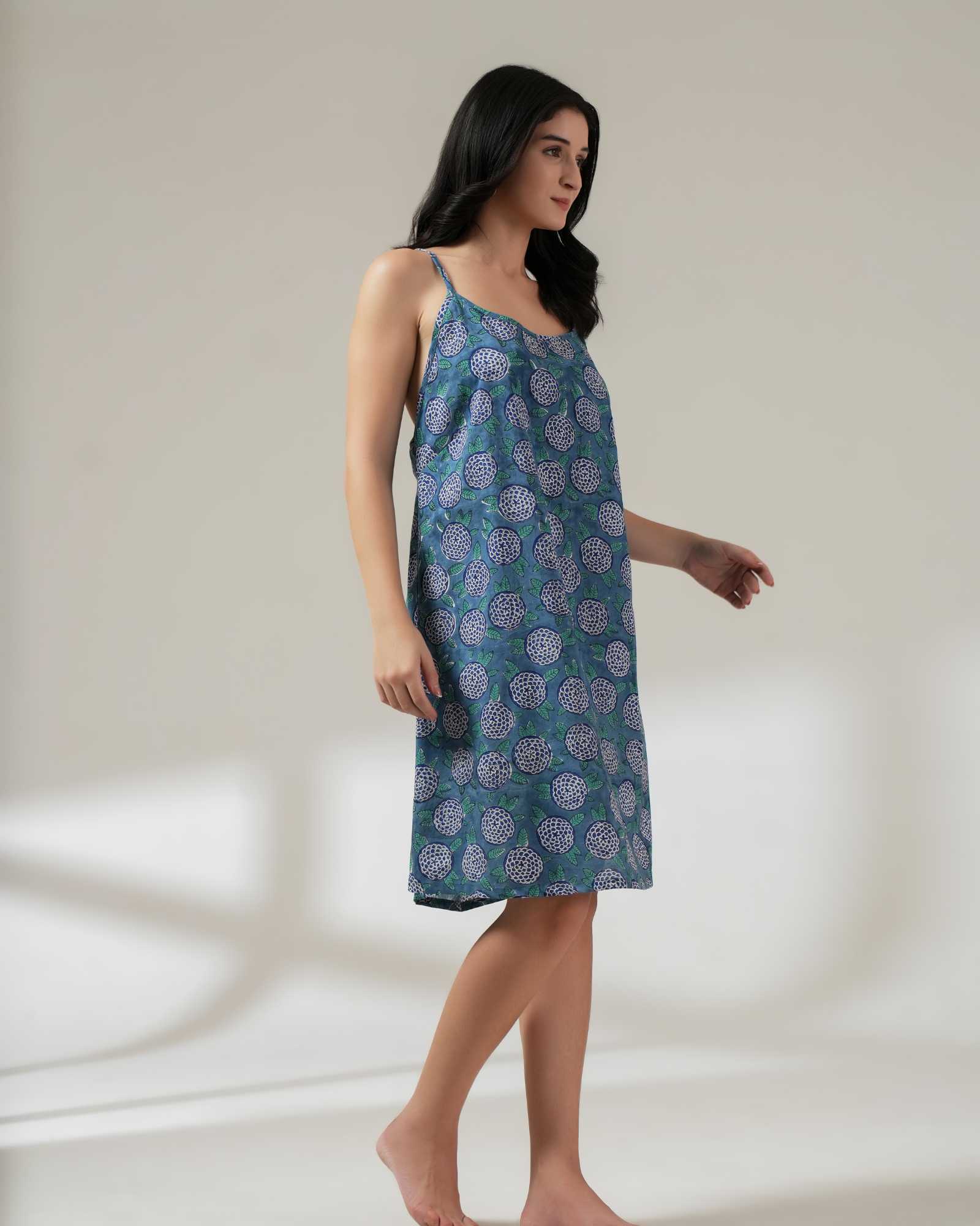 Woman wearing a blue floral nightdress against a plain background