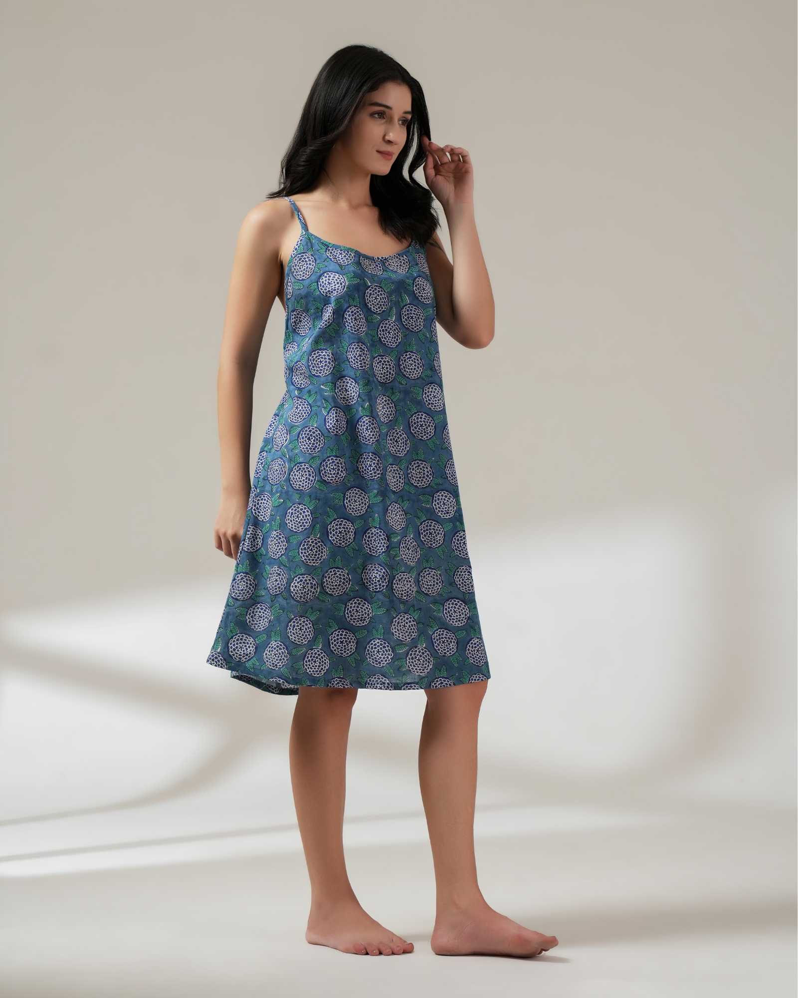 Woman wearing a blue patterned nightgown on a plain background