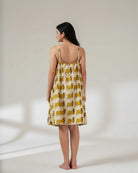Woman wearing a yellow patterned dress on a plain background
