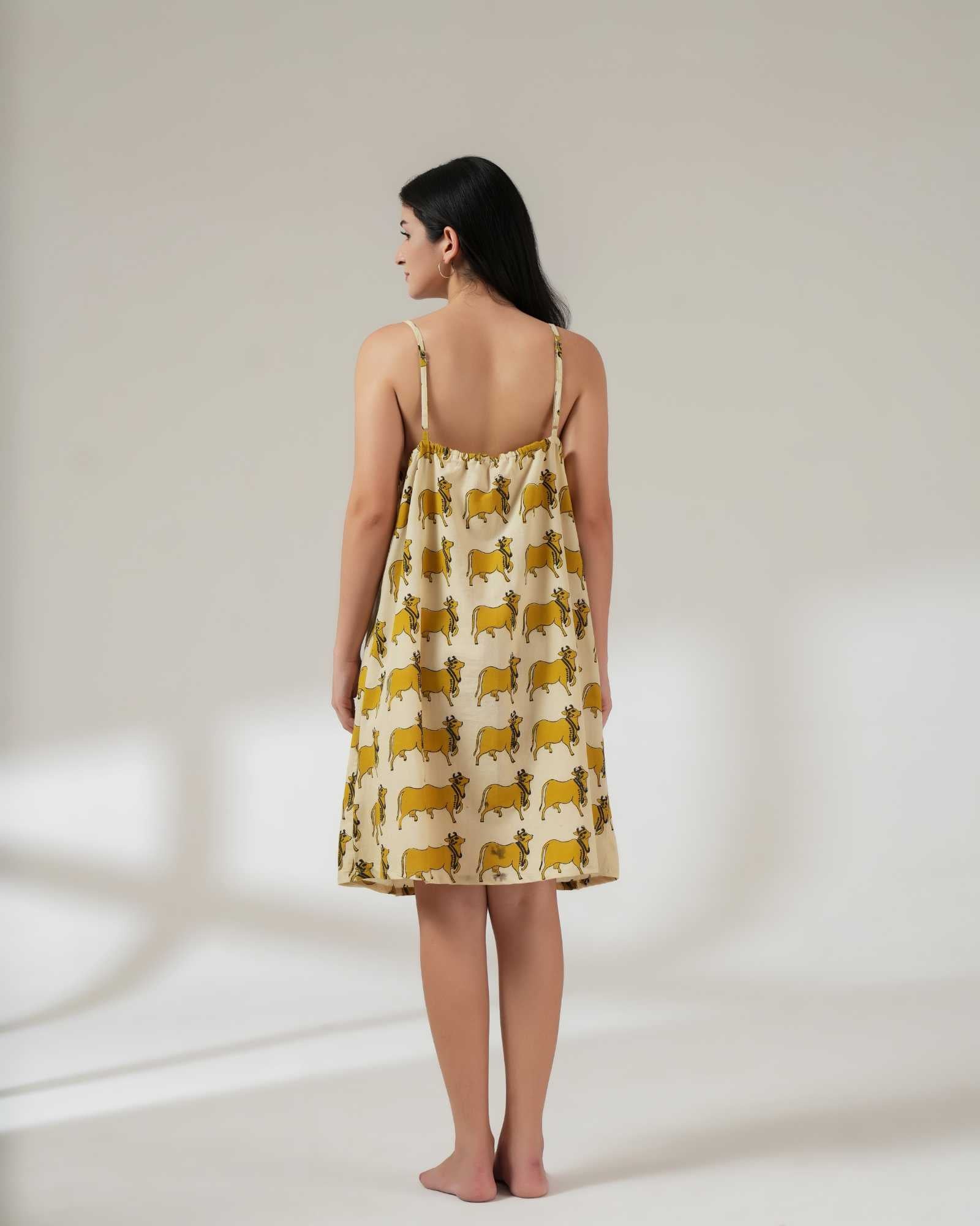 Woman wearing a yellow patterned dress on a plain background