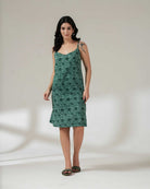 Woman wearing a green floral slip dress on a white background.