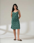Woman wearing a green floral dress against a plain background