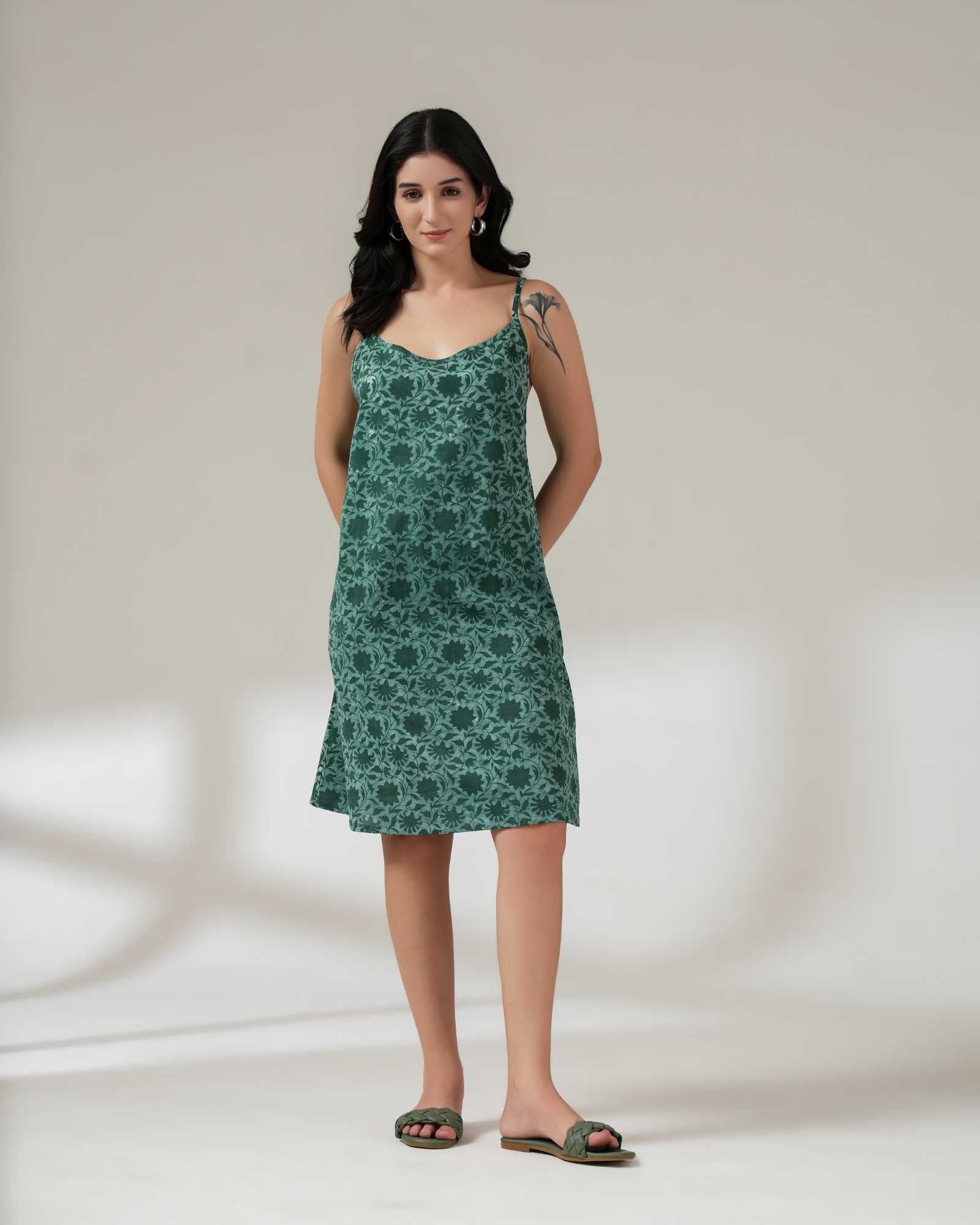 Woman wearing a green floral dress against a plain background