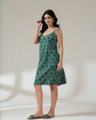 Woman wearing a green floral dress against a plain background