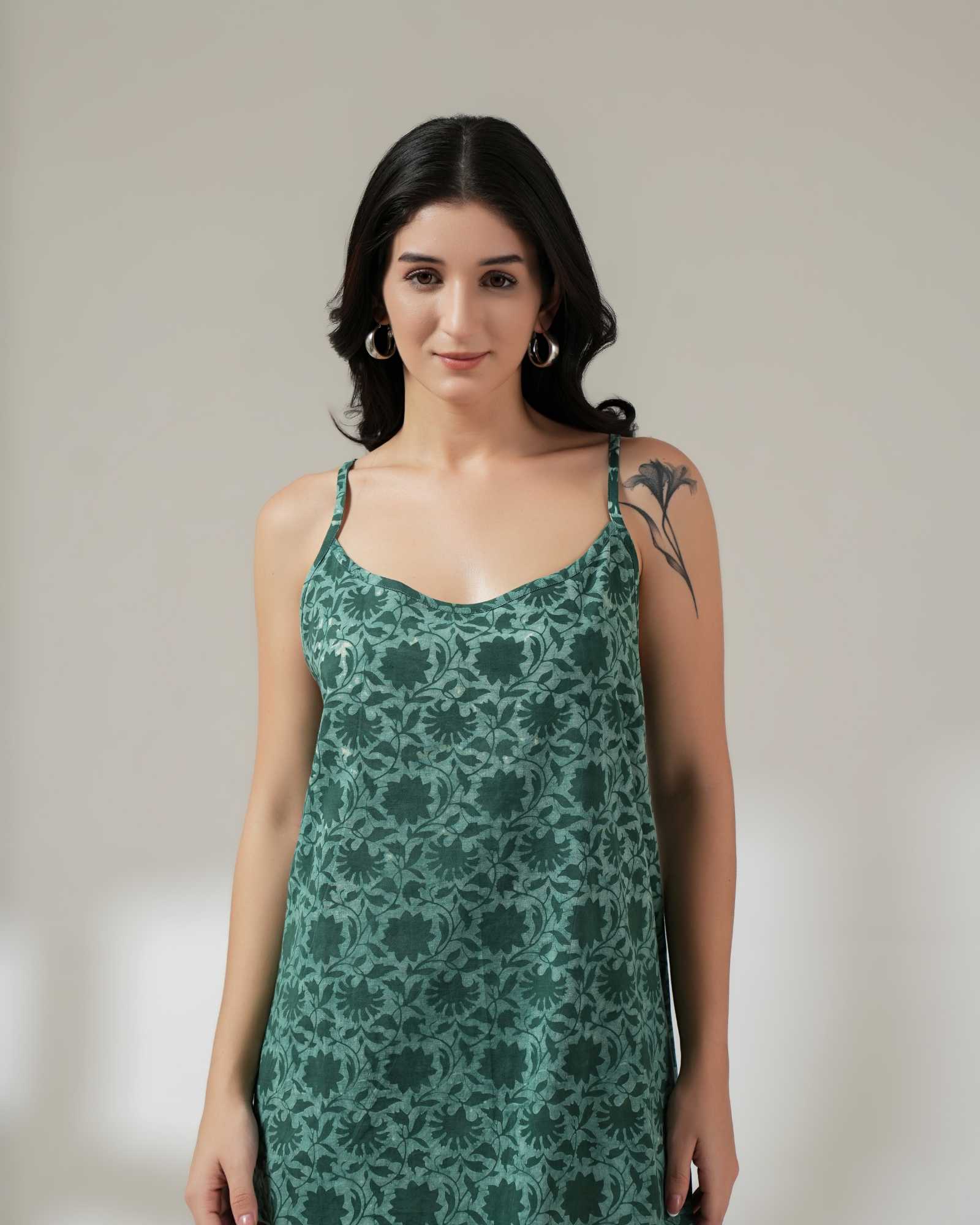 Woman wearing a green floral dress against a plain background