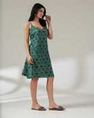 Woman wearing a green floral dress against a plain background