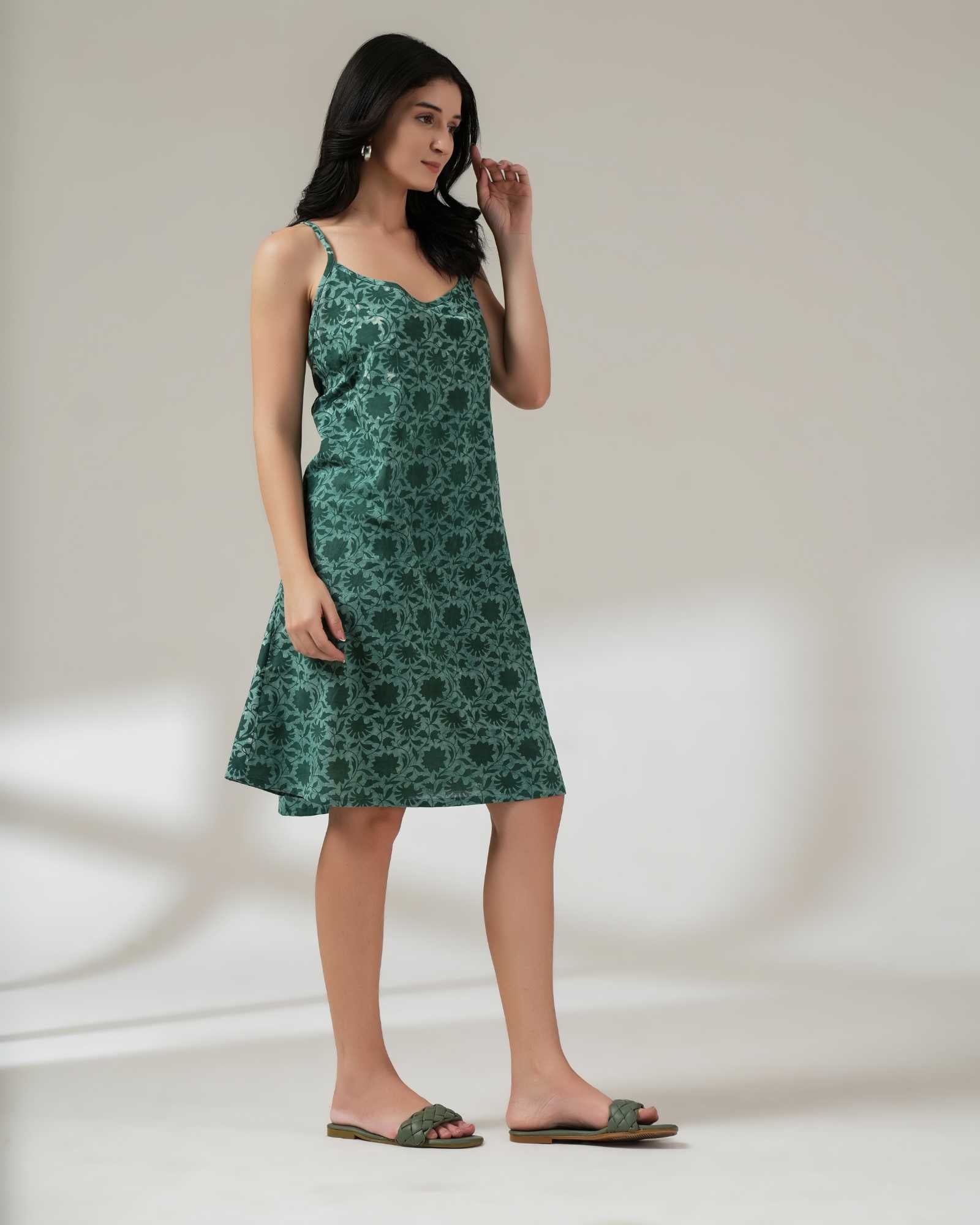 Woman wearing a green floral dress against a plain background
