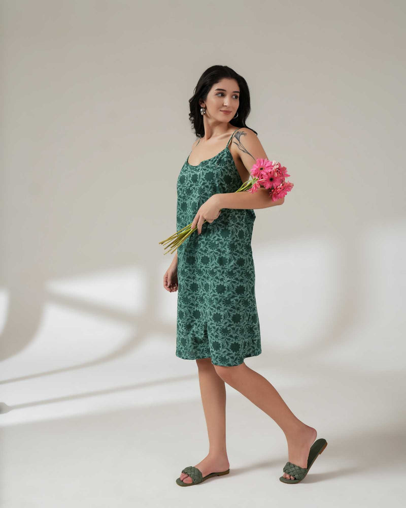 Woman in a green floral dress holding pink flowers against a white background