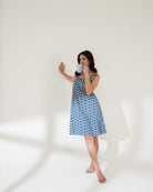 Woman wearing a blue floral dress holding a mug against a white background
