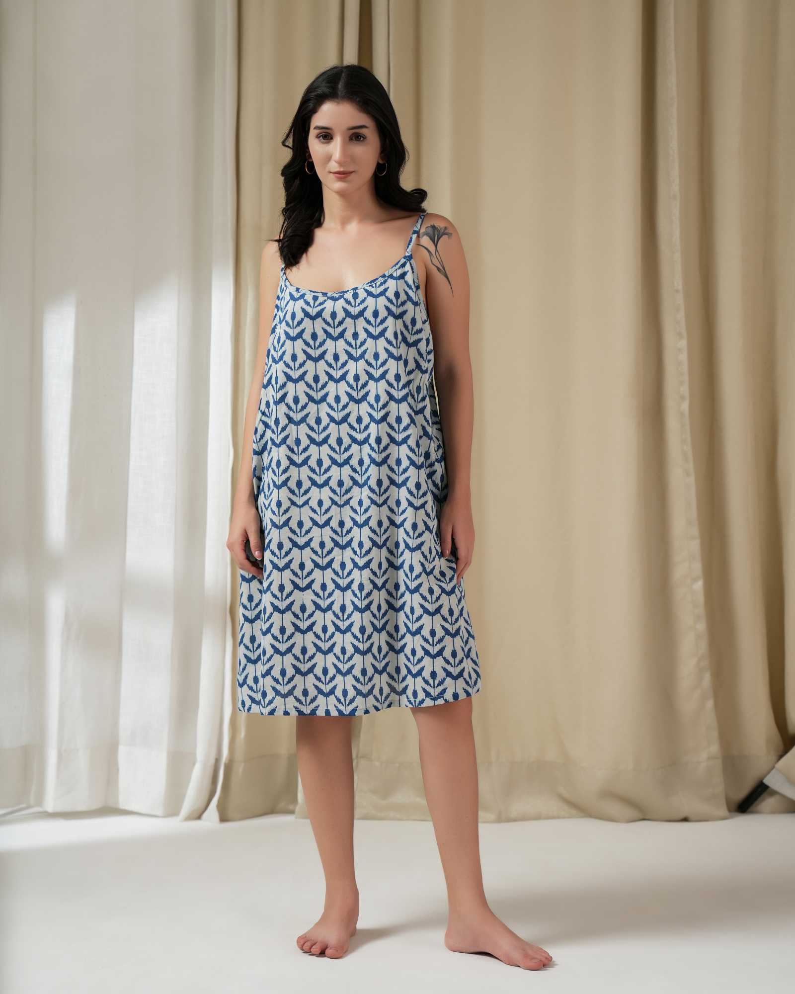 Woman wearing a Indigo Ikkat dress standing in front of beige curtains.