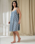 Woman wearing a blue and white patterned dress standing against a neutral background