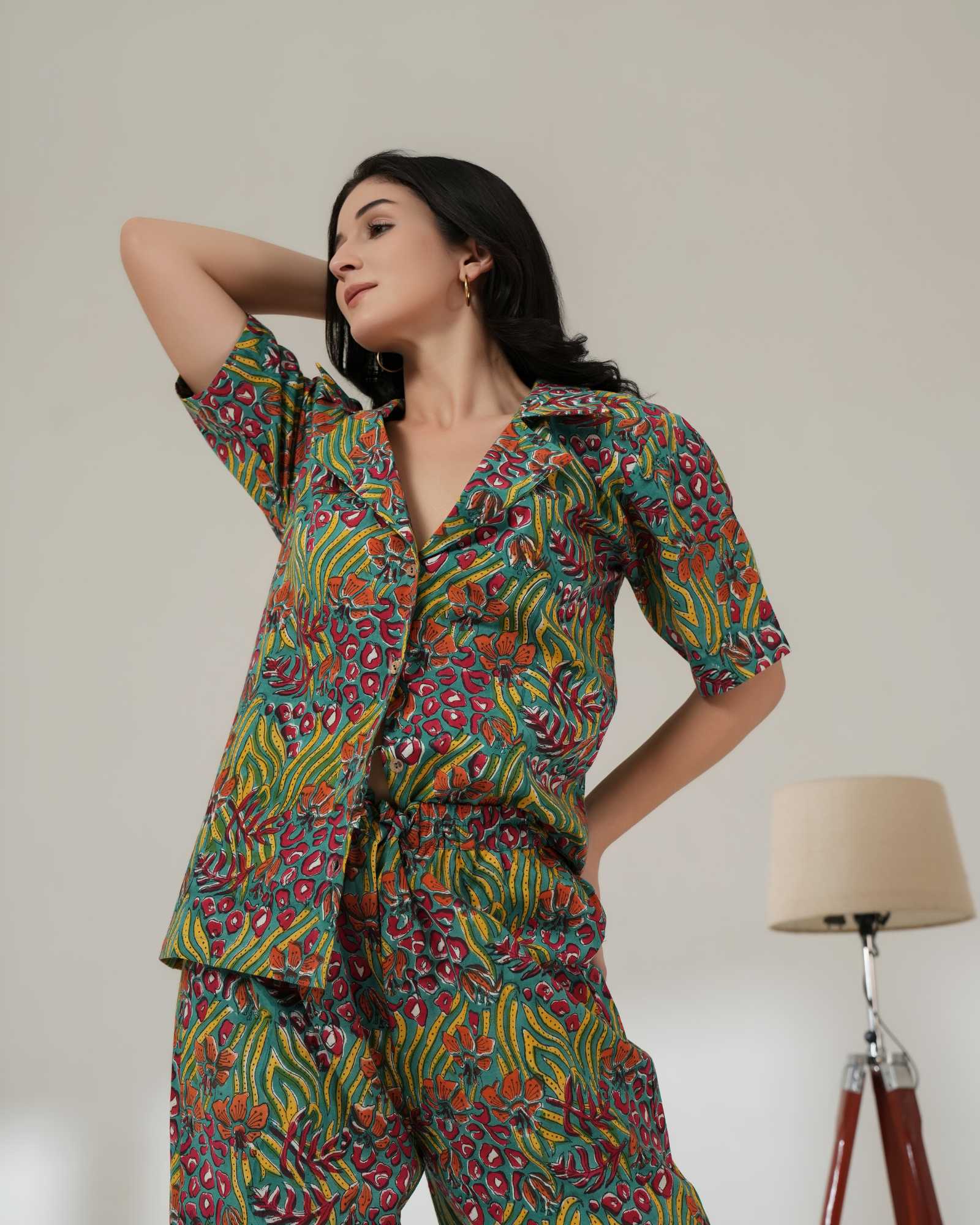 Woman wearing a colorful patterned outfit standing against a plain background