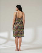 Woman wearing a green patterned slip dress on a plain background