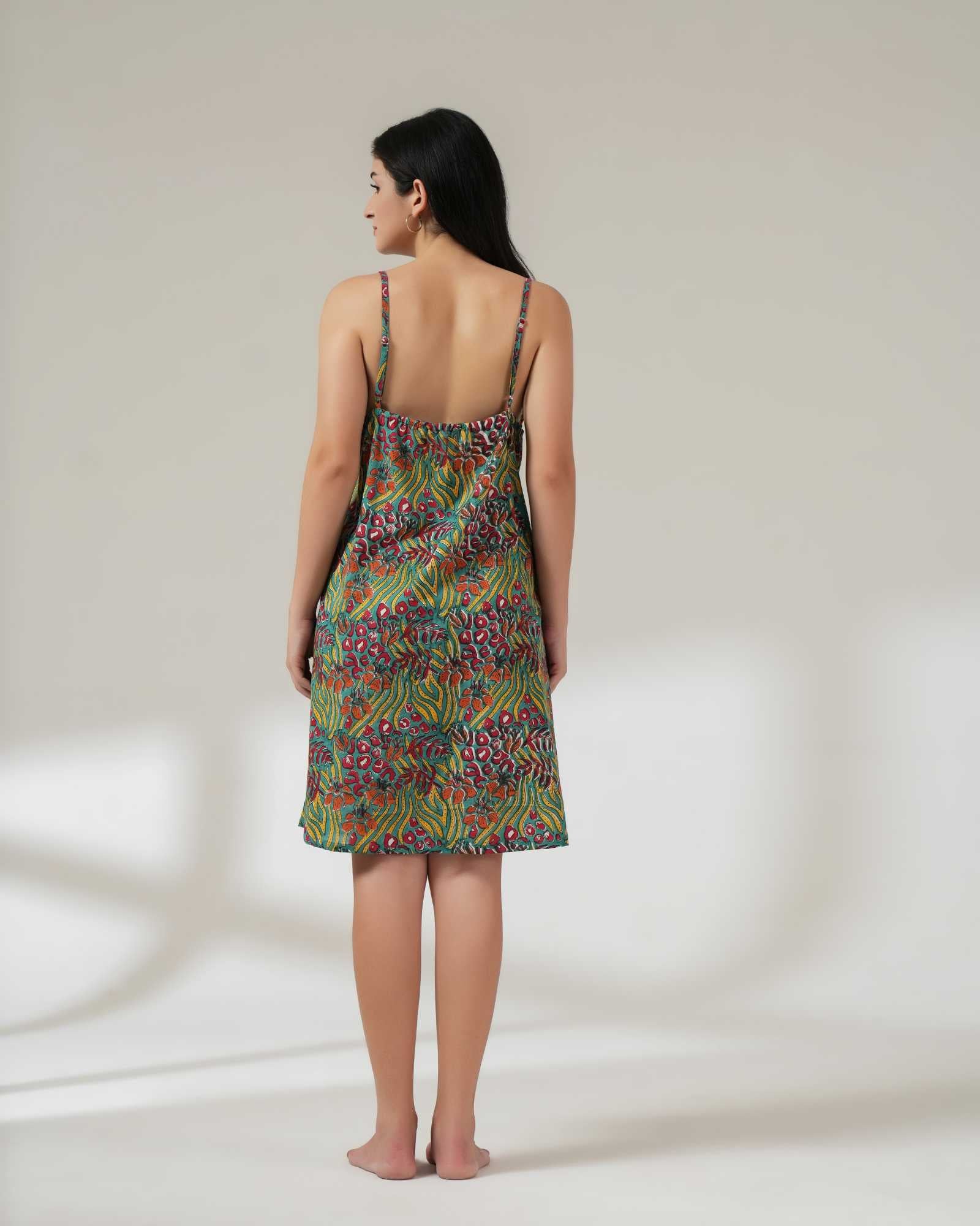 Woman wearing a green patterned slip dress on a plain background