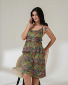 Woman wearing a colorful patterned dress against a plain background