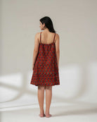 Woman wearing a red patterned dress against a white background