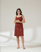 Woman wearing a red patterned dress holding a yellow cup on a white background